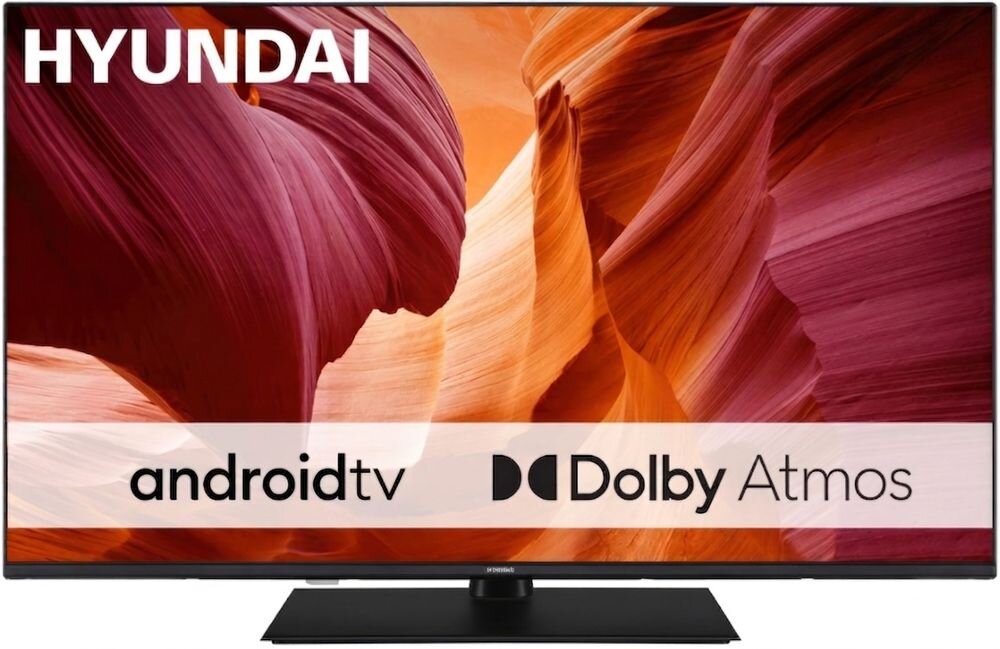 Telewizor z logo HYUNDAI na górze ekranu, wyświetlający obraz skalnych formacji w odcieniach pomarańczowego i czerwonego. Na ekranie widoczny jest tekst: \'android tv\' oraz \'Dolby Atmos\'.