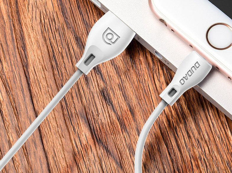 Na drewnianym blacie leży biały kabel micro USB podłączony do urządzenia. Na wtyczce widoczne jest logo \'DUDAO\'.