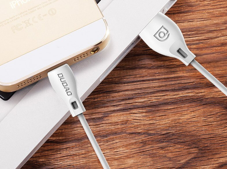 Na drewnianym blacie leży telefon z podłączonym białym kablem USB marki DUDAO. Obok znajduje się drugi kabel z logo producenta na wtyczce.