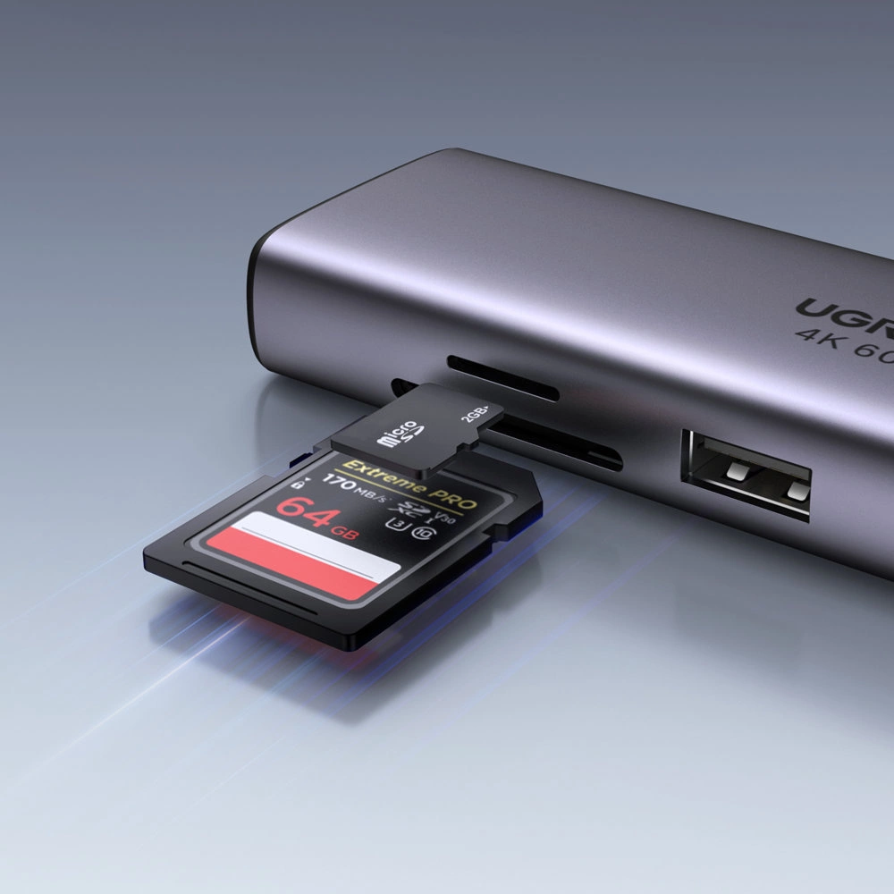 Na obrazie widoczny jest szary hub z logo \'UGREEN 4K 60Hz\', do którego podłączona jest karta pamięci Extreme PRO 64GB oraz adapter microSD 2GB. Obok znajduje się port USB-A.