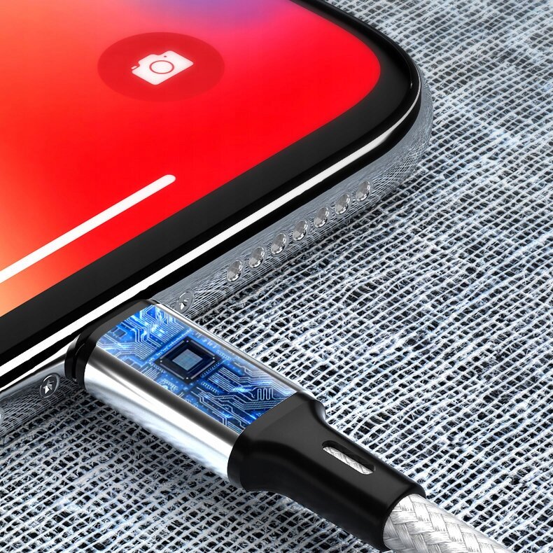 Zbliżenie na kabel USB podłączony do smartfona z czerwonym ekranem i ikoną aparatu. Kabel ma przezroczystą obudowę z widocznymi elementami elektronicznymi.