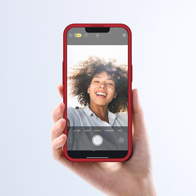 Osoba trzyma smartfon z czerwonym etui, na ekranie widoczna jest aplikacja aparatu z włączonym trybem \'PHOTO\'.