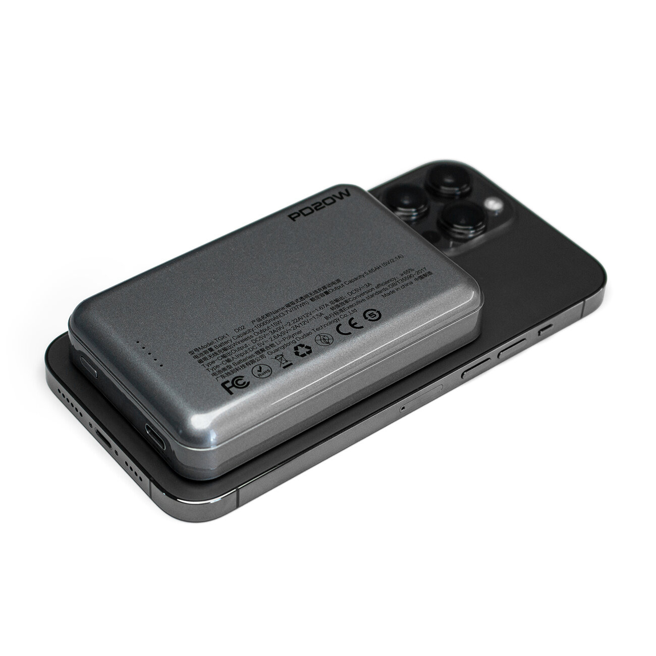 Na obrazie widać czarny powerbank z oznaczeniem \'PD20W\' umieszczony na smartfonie. Na powerbanku widoczne są różne oznaczenia i certyfikaty, takie jak CE i FCC.