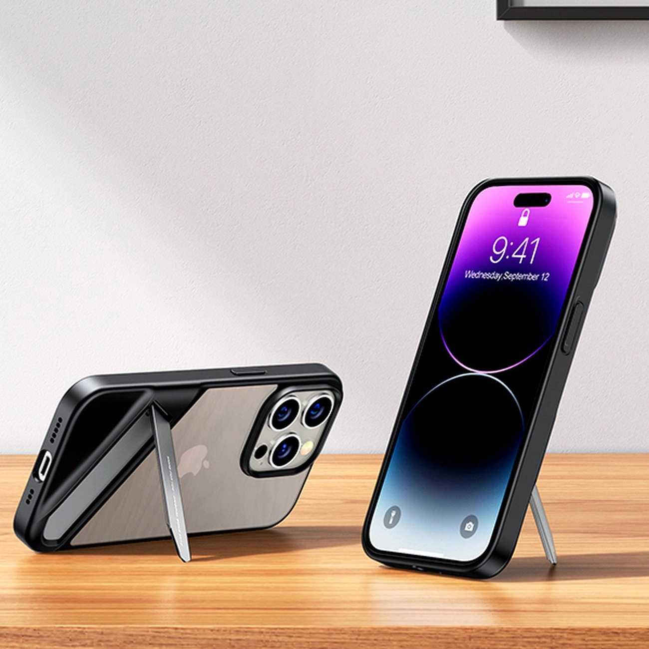 Na drewnianym blacie znajdują się dwa telefony w czarnych etui z wbudowaną podstawką. Jeden telefon jest ustawiony pionowo, a drugi poziomo, oba z widocznymi ekranami i aparatami.