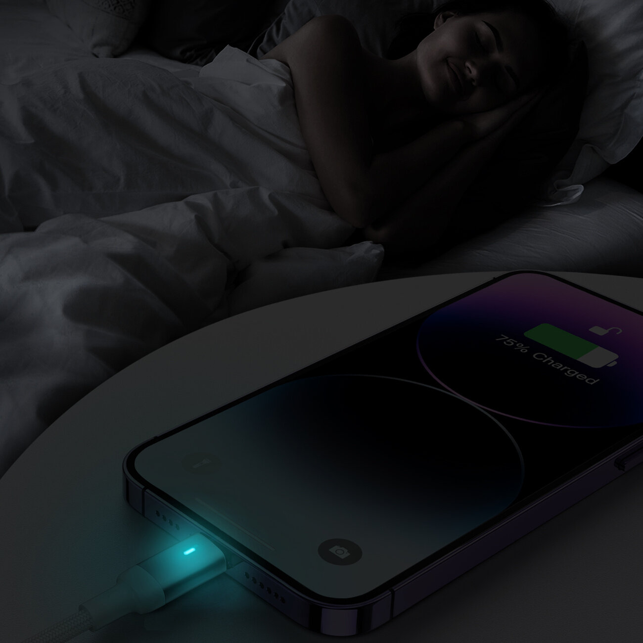 Na stoliku nocnym leży telefon z wyświetlaczem pokazującym ikonę baterii i napis \'75% Charged\'. Do telefonu podłączony jest kabel z podświetlanym na niebiesko wskaźnikiem LED.