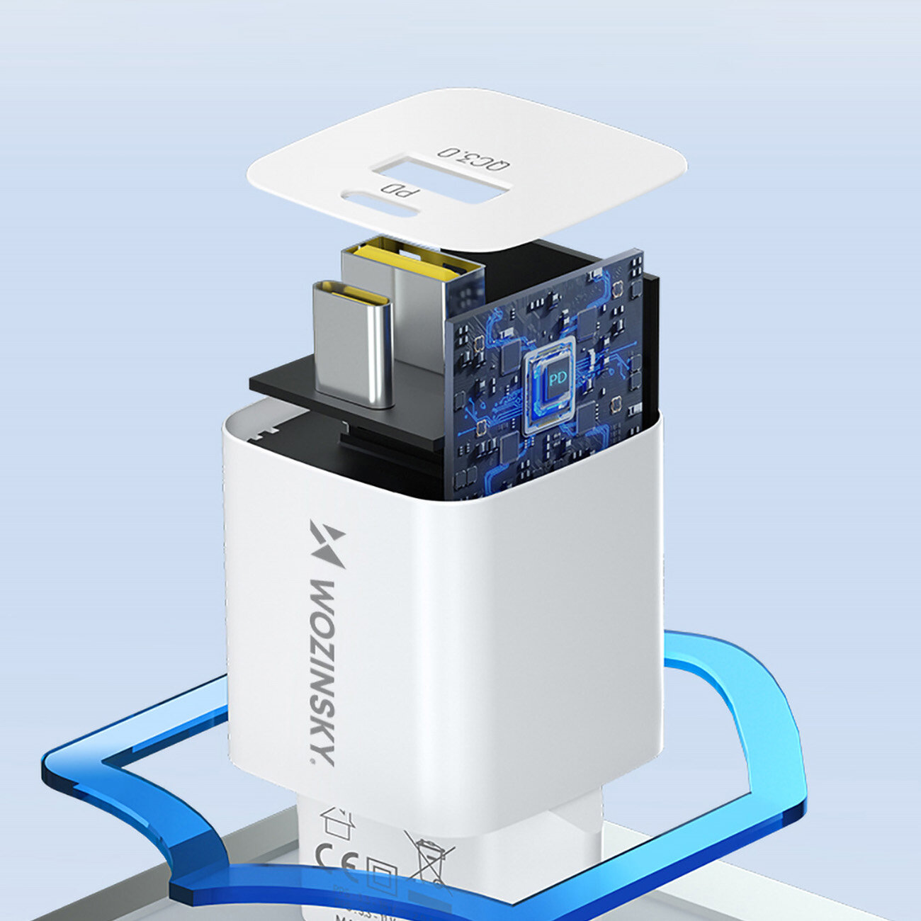 Obraz przedstawia białą ładowarkę sieciową z widocznym wnętrzem, ukazującą elementy elektroniczne i porty USB-A oraz USB-C. Na obudowie widnieje logo \'WOZINSKY\'.