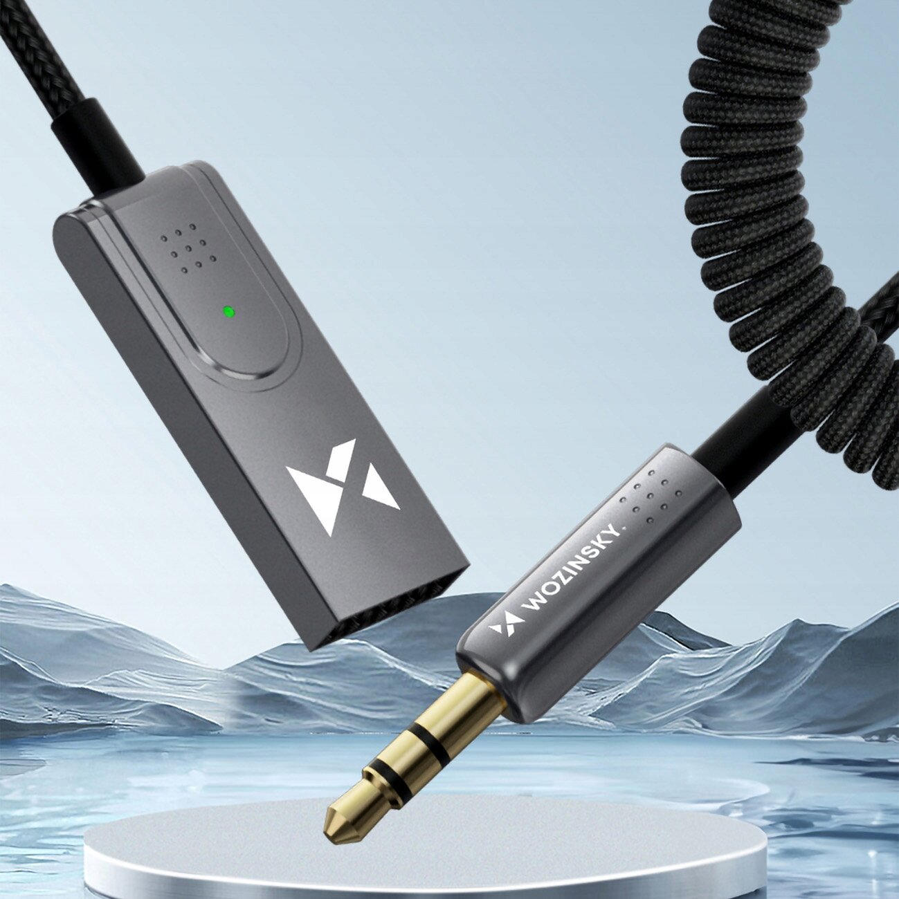 Na obrazie widoczny jest transmiter Bluetooth z logo oraz wtyczką audio. Na wtyczce znajduje się napis \'WOZINSKY\'.