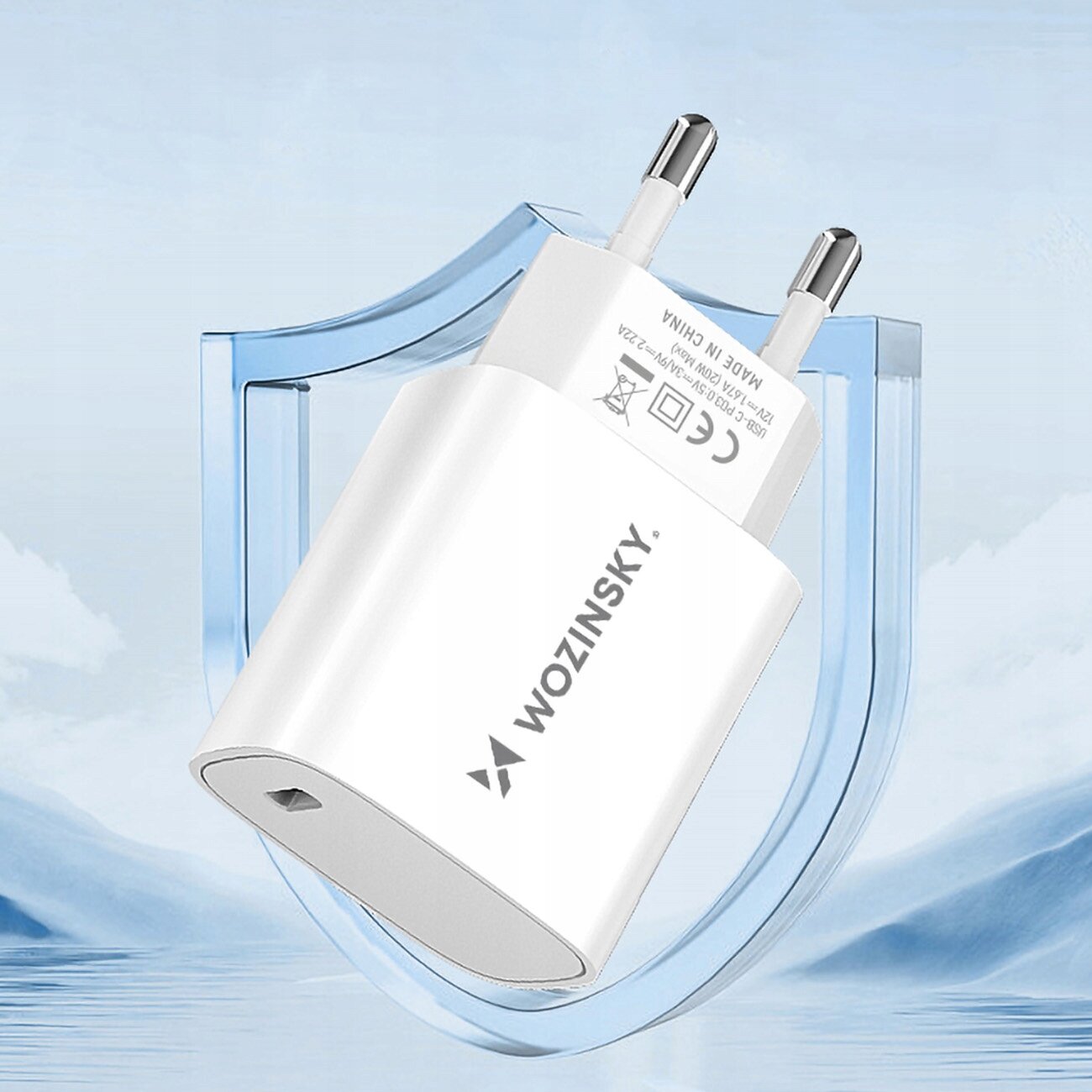 Biała ładowarka sieciowa z logo \'WOZINSKY\' na tle niebieskiego kształtu przypominającego tarczę. Widoczne są dwa metalowe bolce oraz port USB-C.