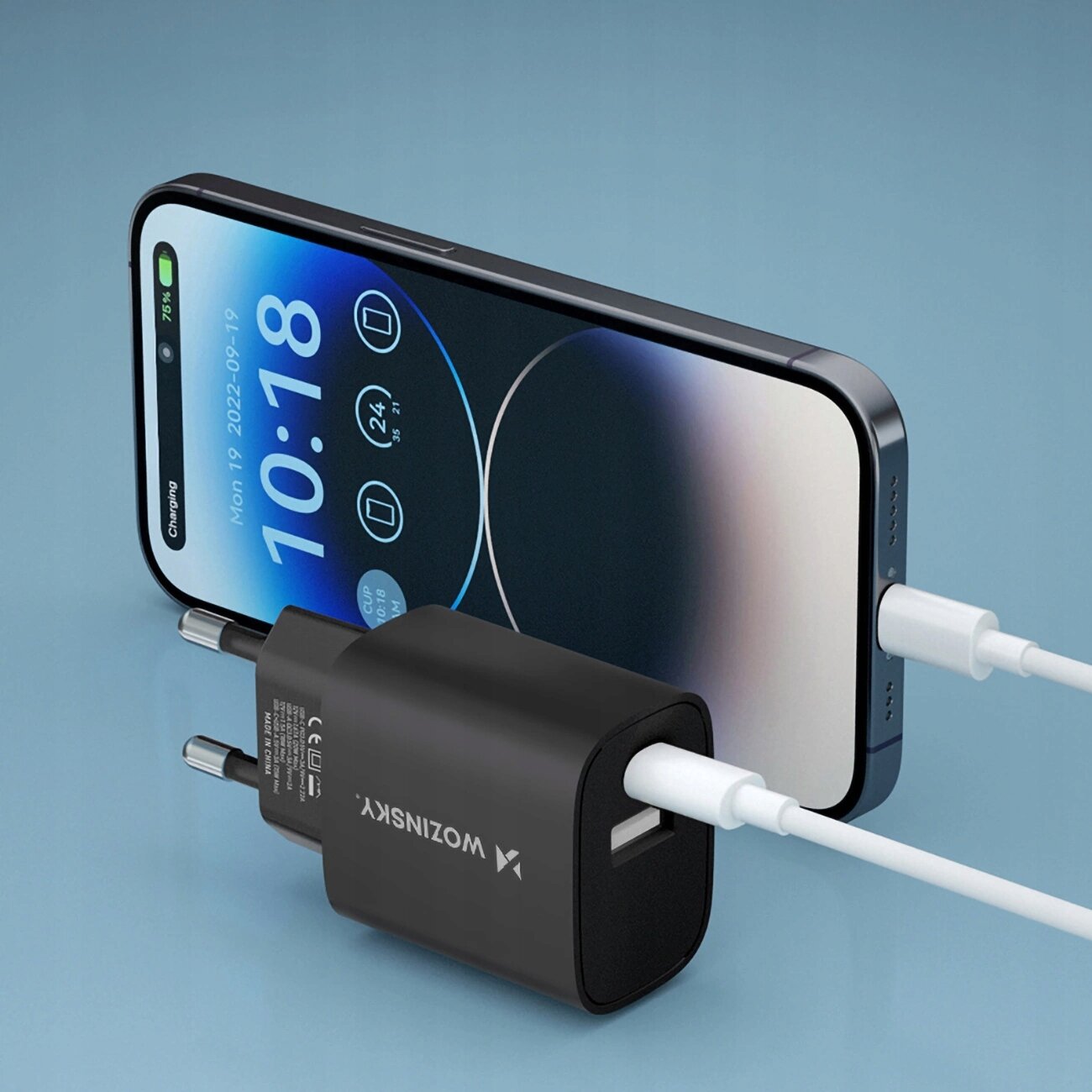 Na obrazie widać czarną ładowarkę sieciową z logo \'Wozinsky\', podłączoną do smartfona za pomocą białego kabla. Ekran telefonu wyświetla godzinę 10:18 oraz datę 2022-09-19.