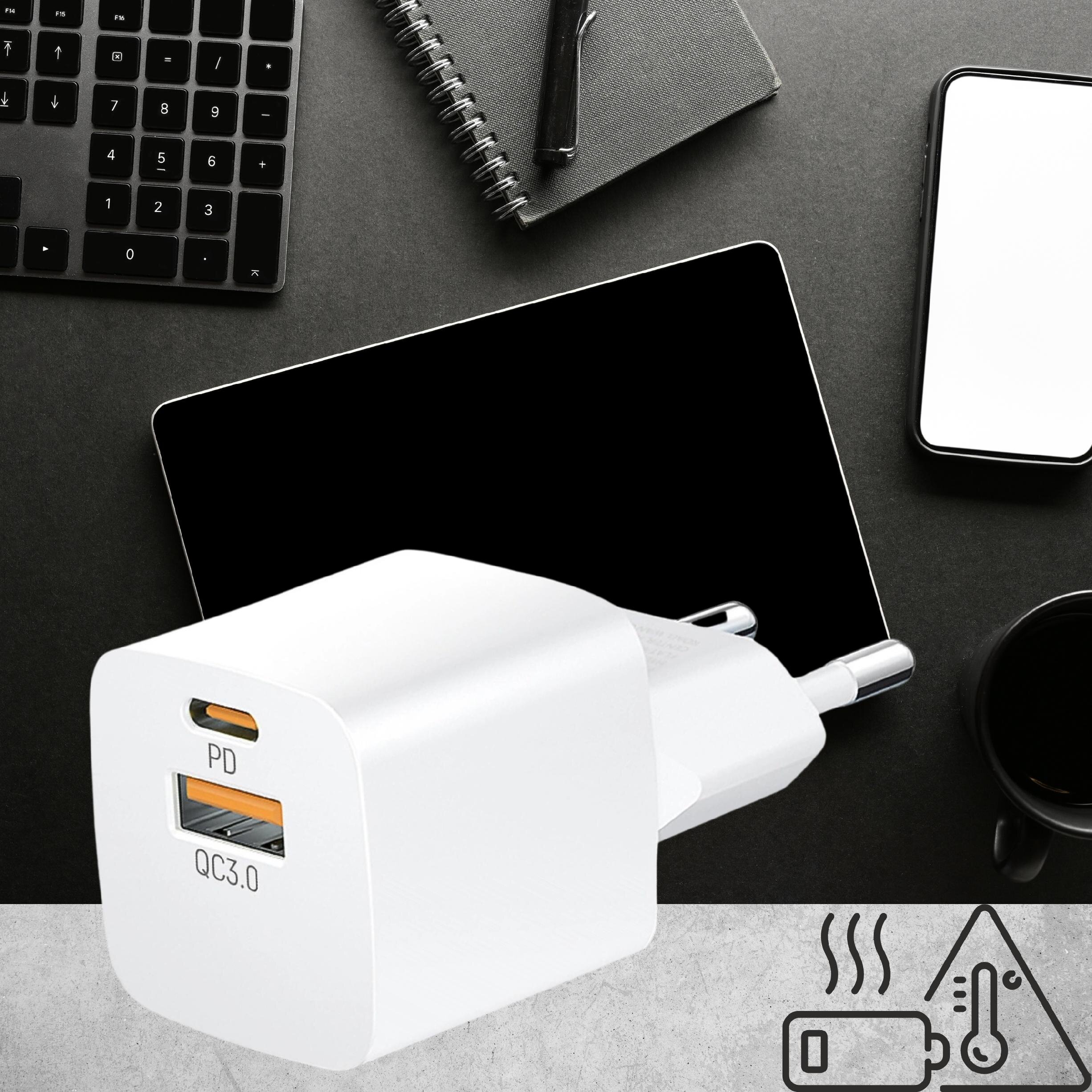 Na obrazie znajduje się biała ładowarka sieciowa z dwoma portami: USB-C oznaczonym jako \'PD\' i USB oznaczonym jako \'QC3.0\'. W tle widoczne są czarne akcesoria biurowe, takie jak klawiatura, notes, długopis, telefon i filiżanka.