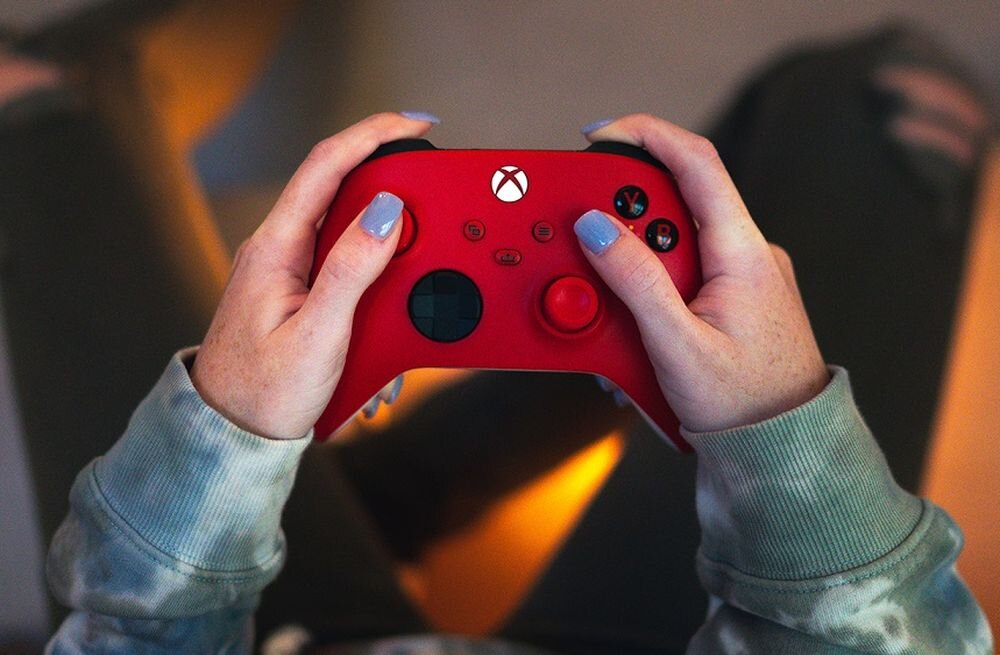 Kontroler MICROSOFT Xbox - kontroler od góry trzymany w ręku na tle dywanu