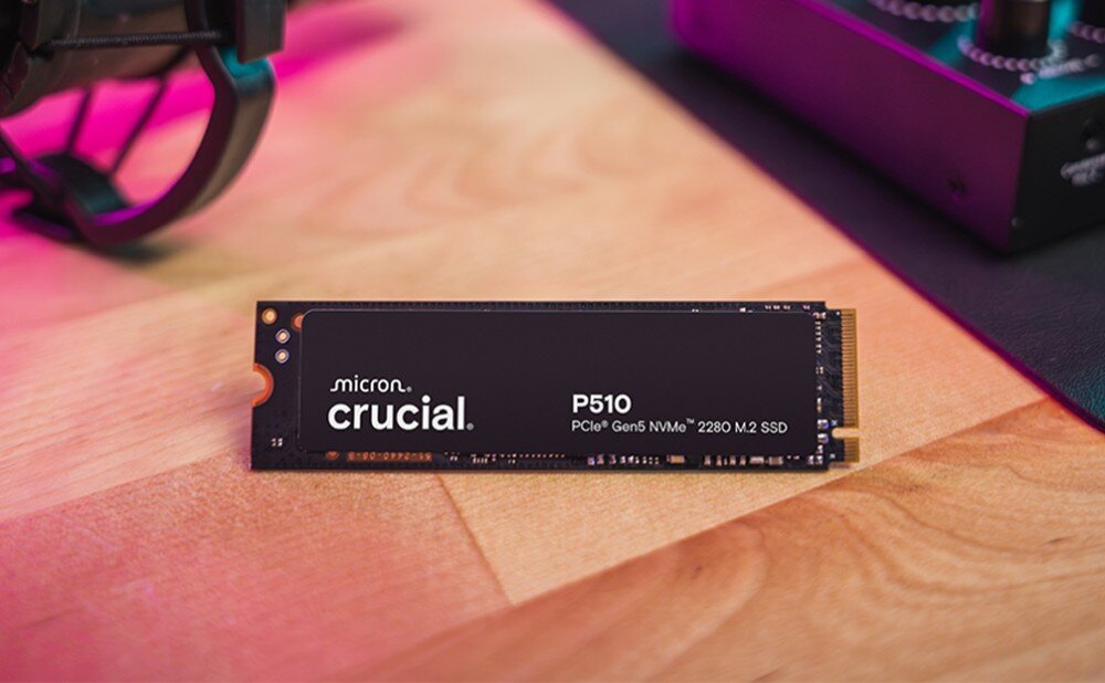 Dysk CRUCIAL P510 Zbliżenie na dysk z logo 'crucial P510' ustawiony na czarnej powierzchni, w tle rozmyte światła RGB i dłoń przy klawiaturze, opis