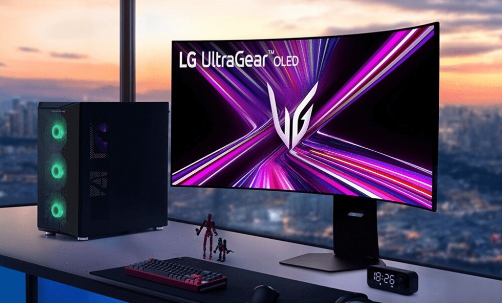 Monitor LG UltraGear 45GX950A-B.AEU Monitor na biurku obok komputera stacjonarnego. Na ekranie logo 'LG UltraGear OLED' na tle dynamicznej, kolorowej grafiki. W tle panorama miasta o zachodzie słońca, wygląd, podstawa, regulacja położenia