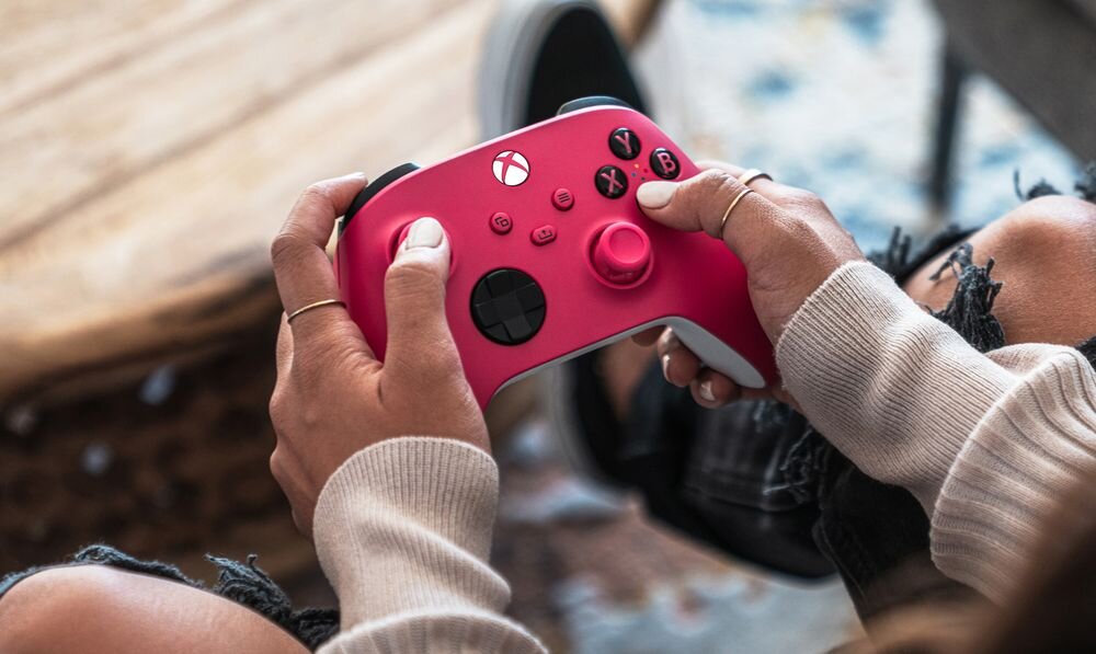 Kontroler MICROSOFT Xbox - kontroler od góry trzymany w ręku na tle dywanu