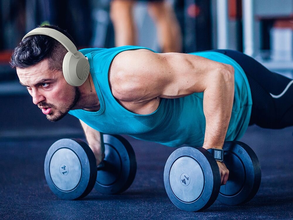 Słuchawki POWERLOCUS Orion Bluetooth 5.4 mikrofon rozmowy sterowanie, osoba z założonymi słuchawkami nausznymi ćwicząca na siłowni