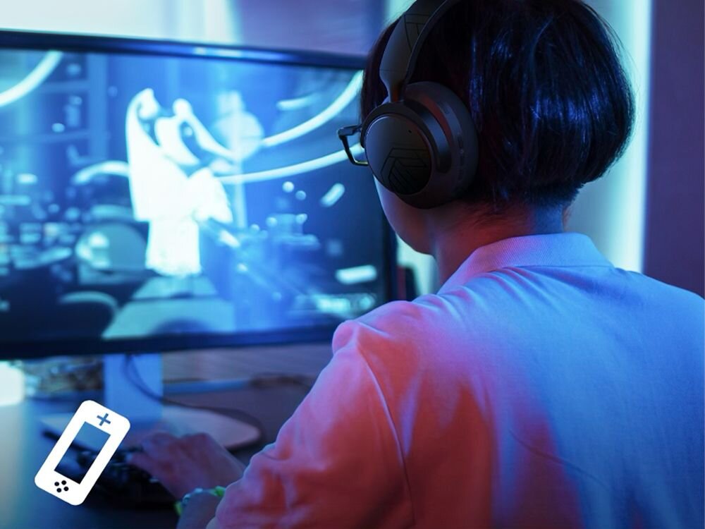 Słuchawki nauszne POWERLOCUS MoonFly elegancki design wysokiej klasy materiały, osoba z założonymi słuchawkami nausznymi grająca na komputerze