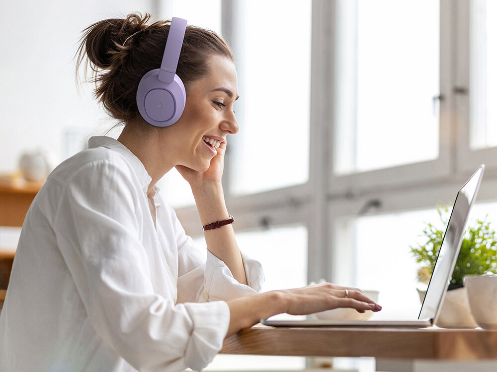 POWERLOCUS Universe miękkie nauszniki memory foam regulowany pałąk składane słuchawki wygodne, osoba z załozonymi słuchawkami nausznymi siedząca przy laptopie