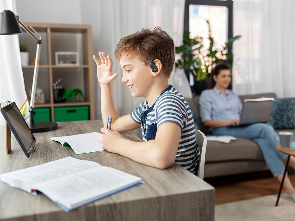 Słuchawki powietrzne POWERLOCUS Jumpy limit głośności 85 dB ochrona słuchu dziecka, dziecko z założonymi słuchawkami odrabiające lekcje