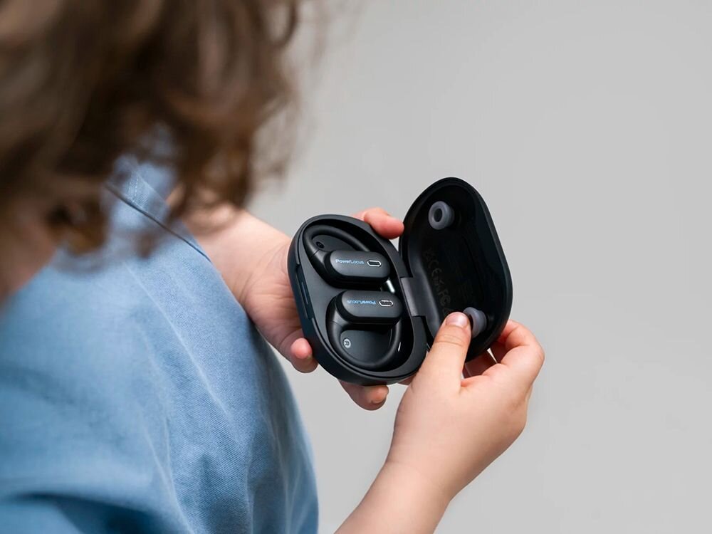 Słuchawki powietrzne POWERLOCUS Jumpy pasmo 20-20000 Hz impedancja 16 Ohm, dziecko trzymające etui ładujące wraz z słuchawkami