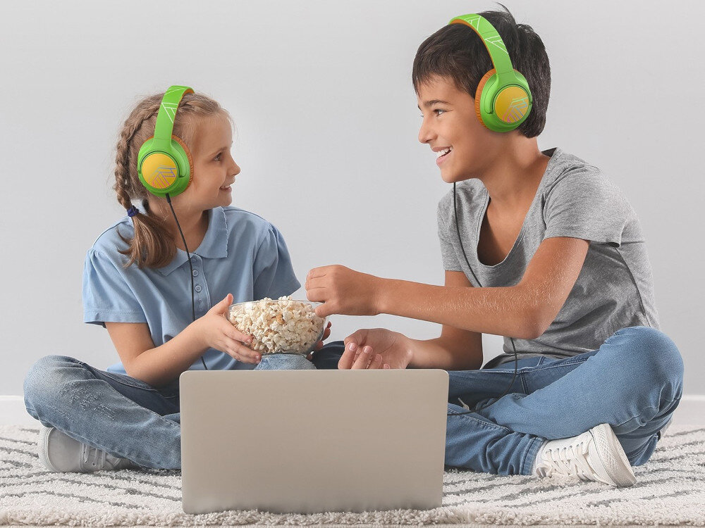 POWERLOCUS Bobo składane słuchawki dla dzieci wytrzymałe prezent kabel USB-C AUX w zestawie, dzieci siedzące po turecku z założonymi słuchawkami nausznymi zajadające się popcornem