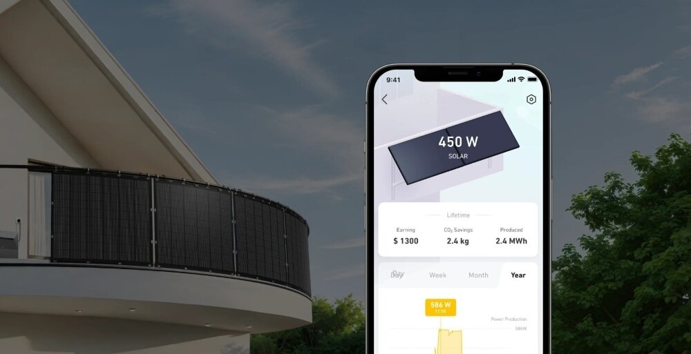 Panel fotowoltaiczny ANKER Solix FS20 900W dom balkon na barierkach panele w tle trawnik drzewa niebo na pierwszym planie telefon z włączoną aplikacją aplikacja ANKER monitorowanie danych inteligentne sterowanie