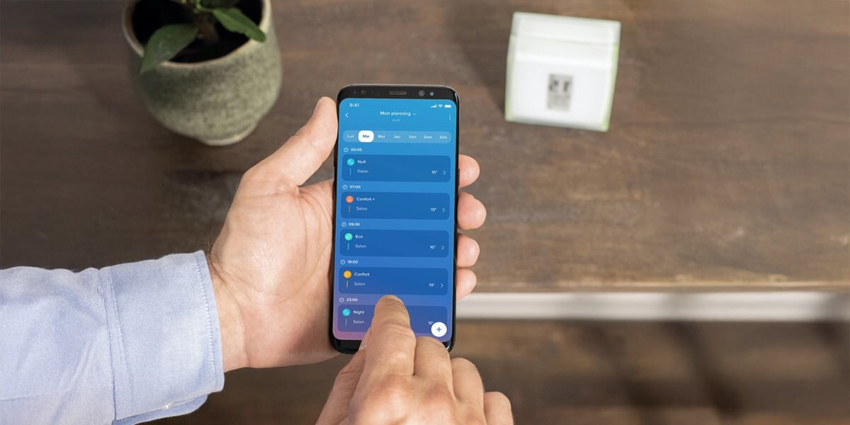 Termostat NETATMO OTH, aplikacje, Energy Home, Control, kontrola, osoba obsługuje smartfon z aplikacją zarządzania termostatem