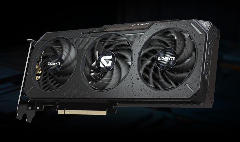 Karta graficzna GIGABYTE GeForce RTX 5060 Ti Gaming OC 8GB Detal tylnej części obudowy, przez otwór widać część układu chłodzenia i krawędź złącza zasilania, płytka PCB, krawędzie, bezpieczeństwo
