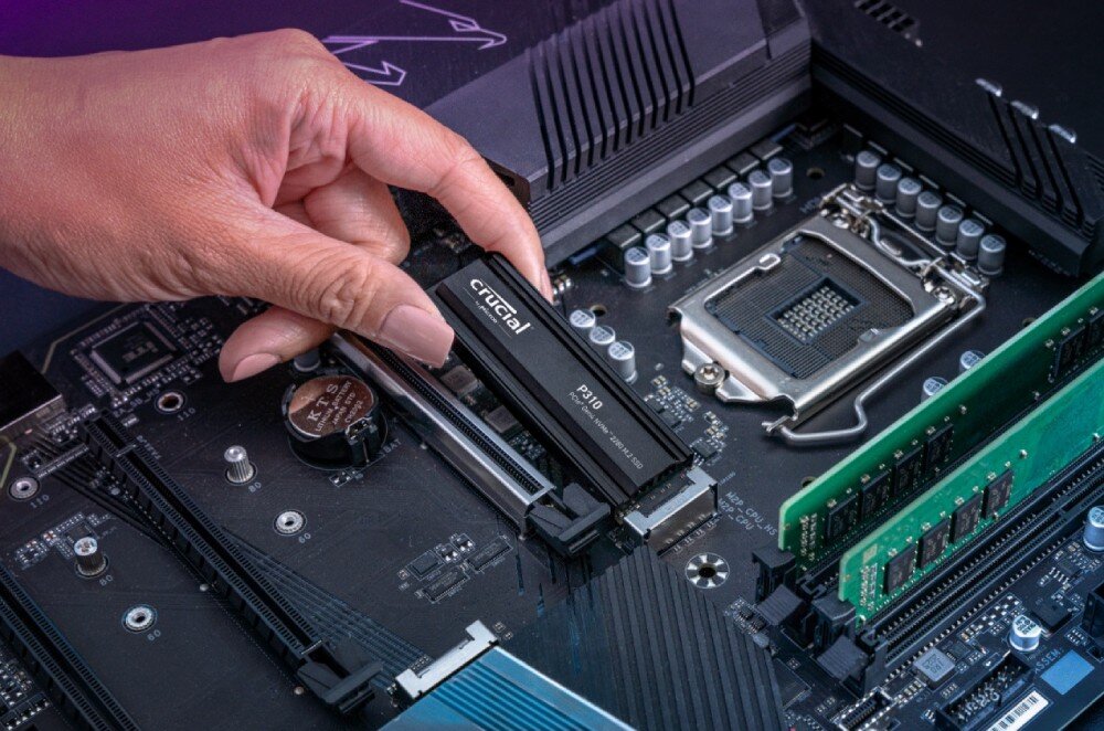 Dysk CRUCIAL P310 Ręka wkłada dysk SSD z napisem 'crucial P310' do gniazda M.2 na płycie głównej komputera, prędkość, wydajność, technologia