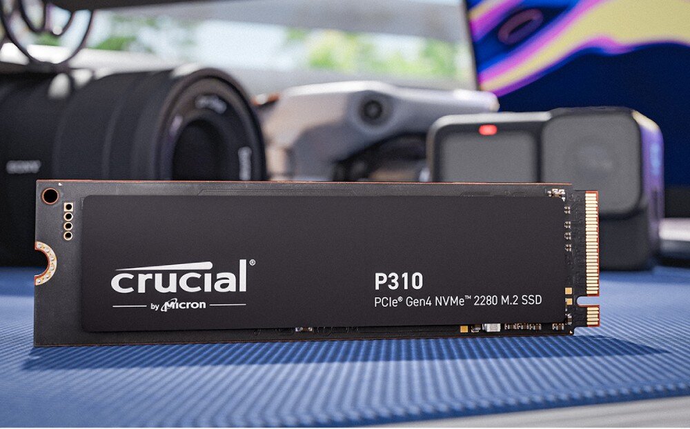 Dysk CRUCIAL P310 Dysk SSD z napisem 'crucial P310 PCIe Gen4 NVMe 2280 M.2 SSD' ustawiony pionowo na niebieskiej powierzchni, w tle obiektywy i kamera, opis