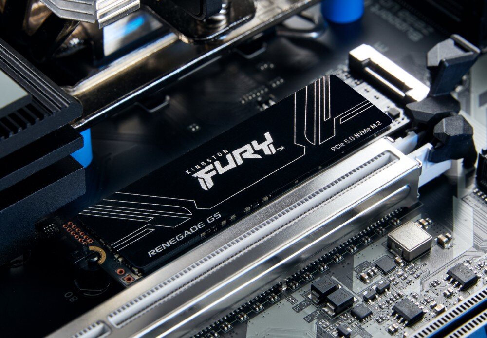 Dysk KINGSTON Fury Renegade G5 Sprzęt zainstalowany w złączu na czarnej płycie głównej, sfotografowany z bliska pod kątem w jasnym, neutralnym oświetleniu obok metalowych elementów chłodzenia i gniazd pamięci RAM, żywotność, trwałość