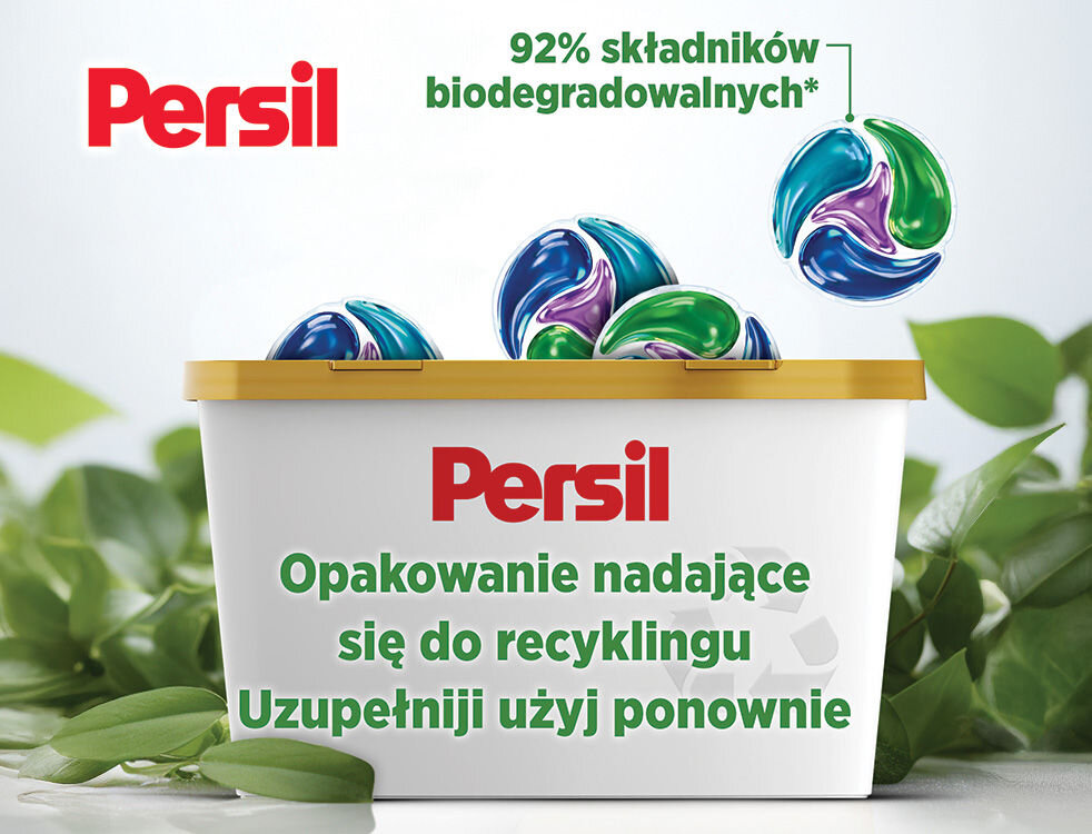 Kapsułki do prania PERSIL Reklama Persil podkreślająca ekologię i recykling. Złoto-białe pudełko na kapsułki wypełnione produktami Persil Discs, otoczone zielonymi liśćmi. Widoczne informacje: 92% składników biodegradowalnych, Opakowanie nadające się do recyklingu, Uzupełnij i użyj ponownie