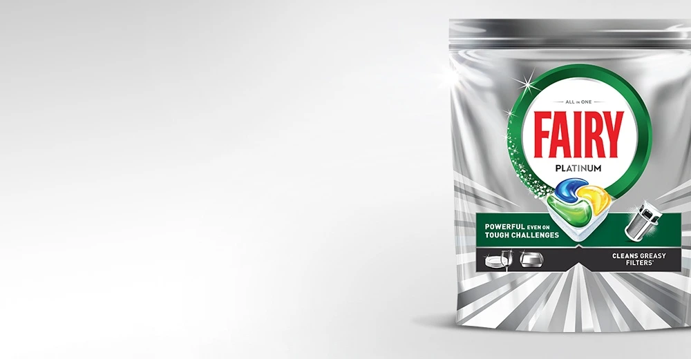 Opakowanie kapsułek do zmywarek FAIRY Platinum All In One z widocznym logo i grafiką kapsułki. Na opakowaniu znajduje się tekst: \'POWERFUL EVEN ON TOUGH CHALLENGES\' oraz \'CLEANS GREASY FILTERS\'.