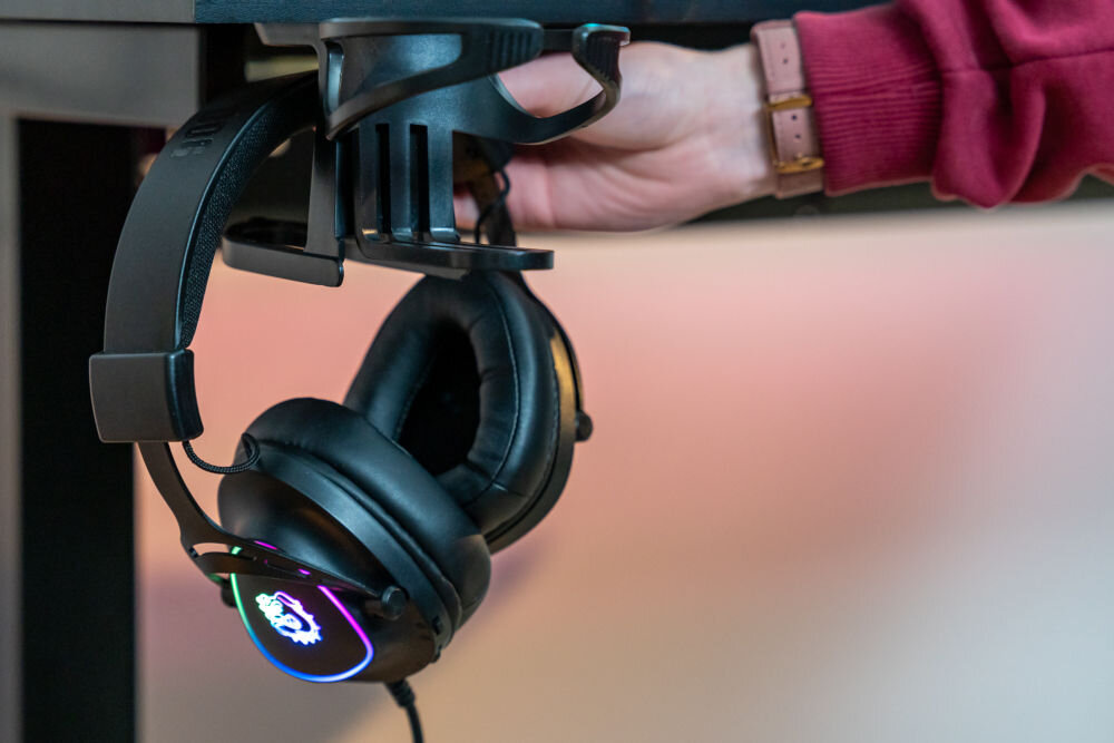 Biurko MAD DOG GD600K Zbliżenie na boczny uchwyt biurka gamingowego z zawieszonymi słuchawkami i miejscem na napój.