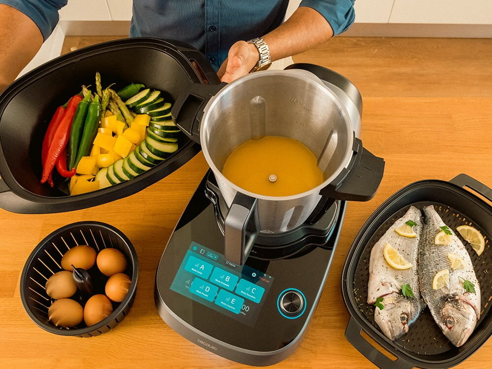 Wielofunkcyjny robot kuchenny CECOTEC Mambo CooKing Total Gourmet robot od góry w użyciu wśród róznych potraw, jedno urządzenie wiele funkcji, oszczędność miejsca na blacie