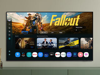 320x240-one-ui-tizen eu Ekran telewizora smart TV Samsung QLED Q7F2AU 2025 z systemem operacyjnym Tizen, widziany od przodu, powieszony na szarej ścianie, a na nim wyświetlane treści i aplikacje.