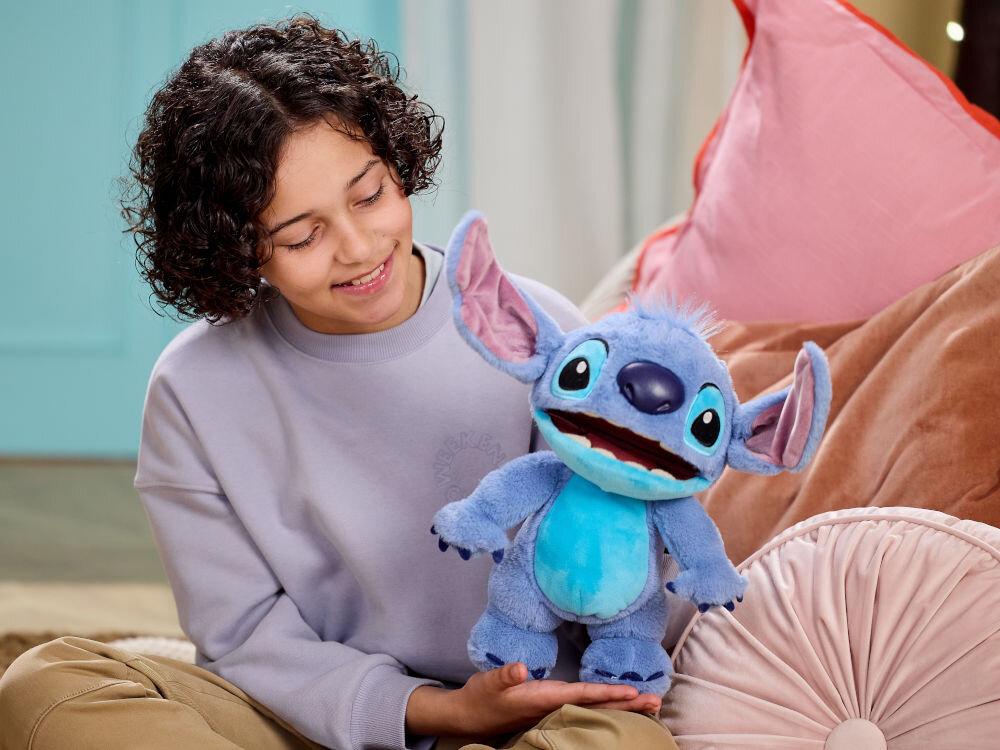 Maskotka WOW Disney Stitch Chatty DIS-1025-01 niebieskie futerko trzymana przez dziecko na kanapie interaktywne funkcje delikatna dla skóry trwała realistyczne detale