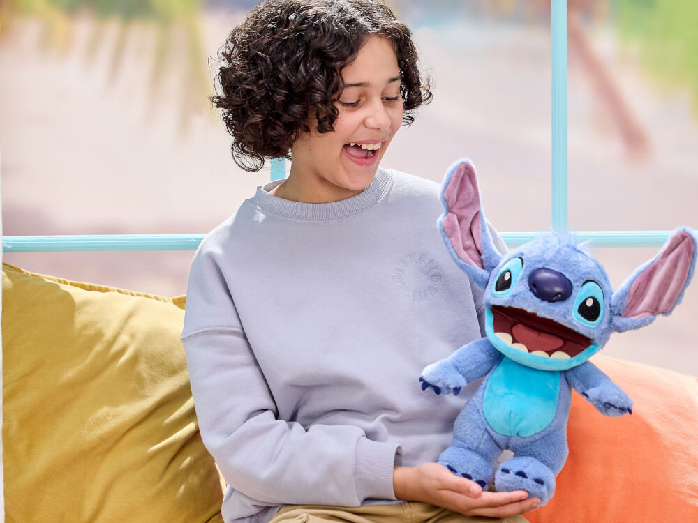 Maskotka WOW Disney Stitch Chatty DIS-1025-01 trzymana przez uśmiechnięte dziecko reakcja na dotyk reakcja na dźwięk odgrywanie scenek interaktywna zabawka
