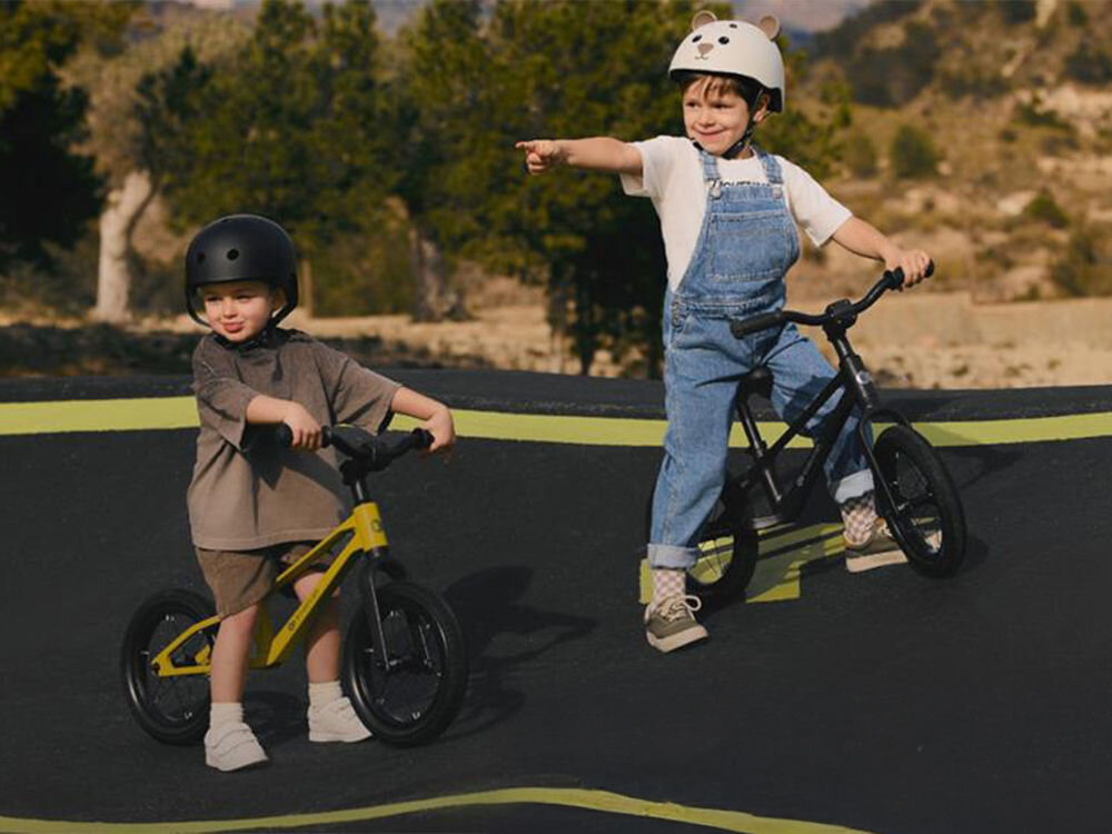 Rowerek biegowy KINDERKRAFT Eter Zielony dwójka dzieci na rowerkach dziewczynka pokazuje palcem sportowy charakter przemyślana konstrukcja dla dzieci już od 2 roku życia Lekka rama z wytrzymałego nylonu doskonalenie koordynacji i równowagi funkcjonalny towarzysz małych odkrywców