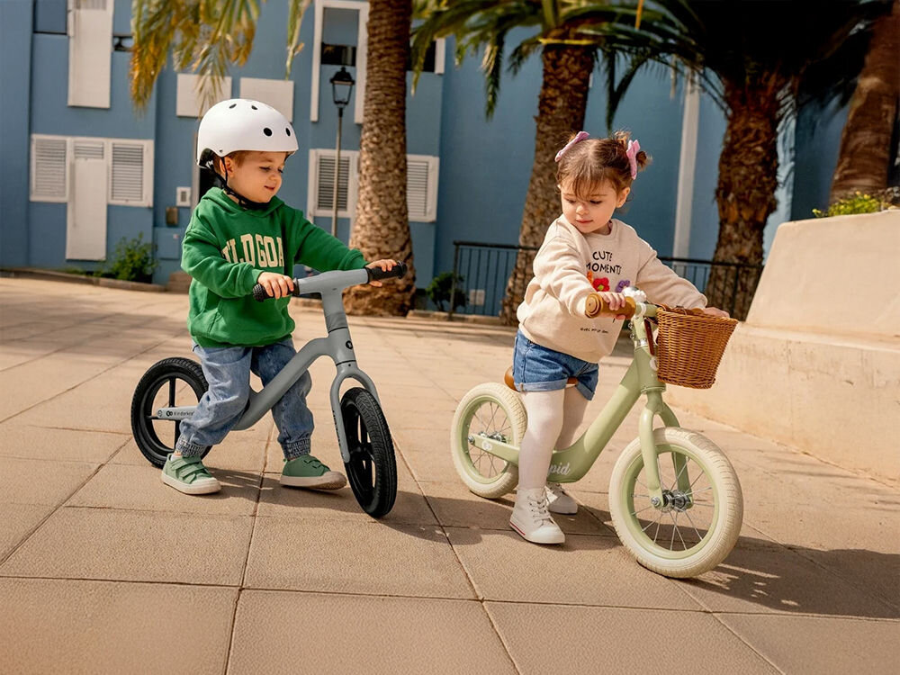 Rowerek biegowy KINDERKRAFT Rapid 2 Różowy dwójka dzieci na rowerkach chłopiec na niebieskim rowerku a dziewczynka na zielonym z koszykiem wygoda wyrazisty styl koszyk klasyczne wzornictwo na ulubione zabawki przekąski inne drobiazgi Montaż jest szybki i intuicyjny bezpieczne przechowywanie skarbów klasyka funkcjonalność  