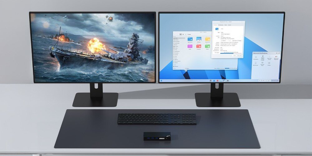 Komputer QOOBE SUC N150 Komputer ustawiony na środku biurka, połączona z dwoma monitorami wyświetlającymi grę wojenną i system operacyjny, pamięć RAM, zintegrowana karta graficzna