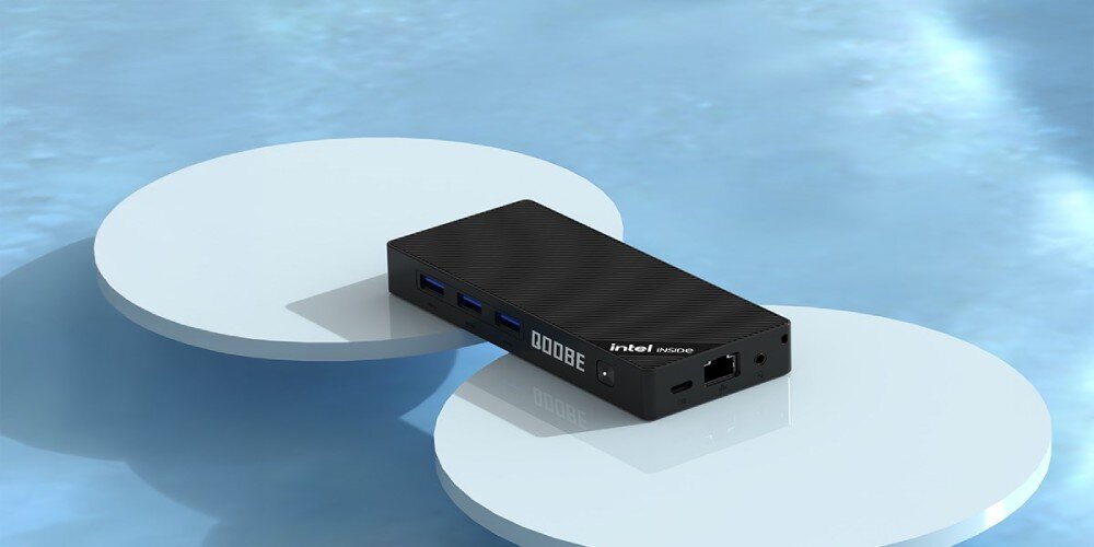 Komputer QOOBE SUC N150 Komputer z logo 'QOQBE' i 'Intel Inside' ustawiona na dwóch białych okrągłych platformach na tle błyszczącej powierzchni, łączność, Wi-Fi, Bluetooth, porty