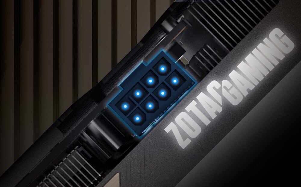 Karta graficzna ZOTAC Gaming GeForce RTX 5060 Ti Twin Edge OC 8GB Zbliżenie na złącze zasilania 8-pin na karcie graficznej. Wokół złącza widoczne delikatne niebieskie podświetlenie. Obok znajduje się napis 'ZOTAC GAMING', architektura, technologia, rdzenie CUDA, taktowanie, zasilanie