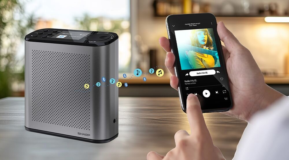 Radio SHARP DR-P530 Bluetooth 5.3 głośnik bezprzewodowy podcasty muzyka, radio stojące na drewnianym stole, osoba trzymające w ręku smartfon