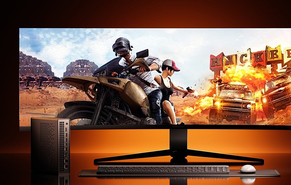 Komputer MINISFORUM MS-A1 Pionowy Mini PC obok szerokiego monitora wyświetlającego scenę z gry akcji na pustyni