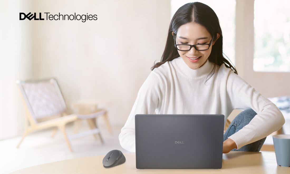 Osoba pracuje na laptopie Dell Pro z myszą bezprzewodową przy biurku w jasnym wnętrzu podczas pracy zdalnej.
