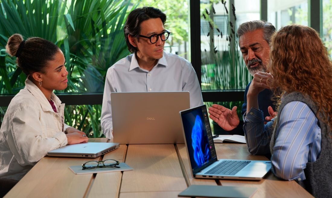 DELL Pro 13 Plus z zespołem biznesowym dyskutującym przy stole konferencyjnym z DELL laptopami, demonstrując szybki dysk SSD do pracy korporacyjnej i współpracy grupowej - dysk SSD