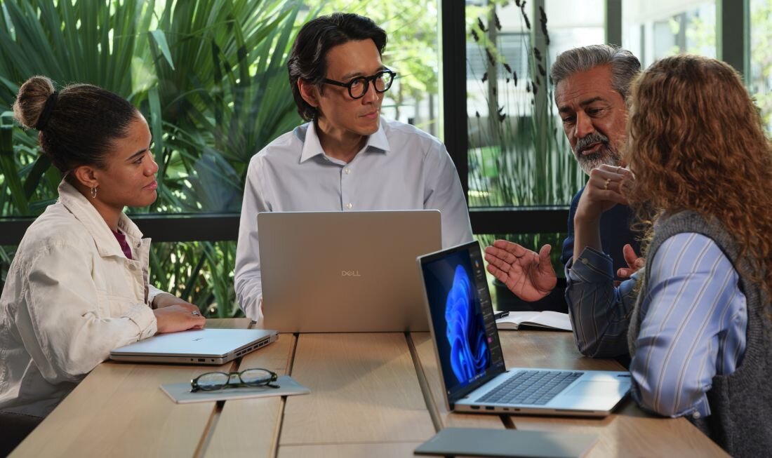 Zespół czterech osób prowadzi spotkanie biznesowe z laptopami DELL Pro 14 Plus PB14250 BTO212 w biurze – DELL Management Portal integracja Microsoft Intune zdalne zarządzanie flotą