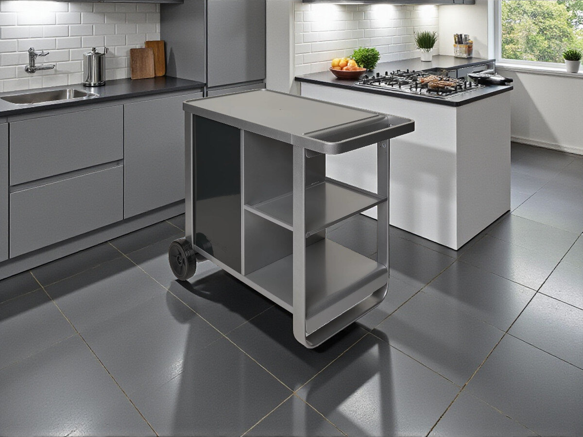Wózek do grilla CAMPINGAZ Plancha Deluxe 2213920, stabilność, mobilność, przestrzeń, grillowanie, Srebrno-szary metalowy wózek kuchenny na czterech czarnych kółkach z czarnymi drzwiami po lewej stronie, otwartymi półkami po prawej i górnym blatem.