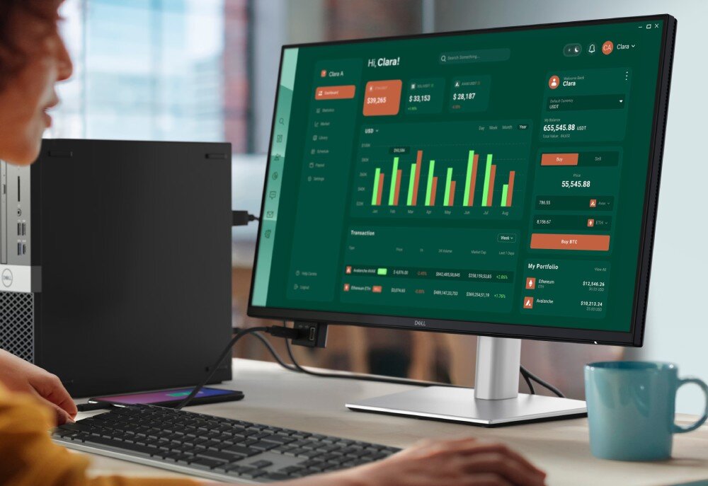Monitor DELL P2425D Dwa połączone ze sobą monitory stojące na biurku, wyświetlające program pocztowy oraz arkusz kalkulacyjny, obsługiwane przez osobę w słuchawkach