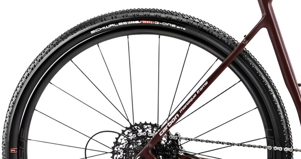 Rower gravel ROMET Nyk U22 28 cali Brązowo-beżowy 2024 zbliżenie na tylną oponę rozmiar koła 28 cali opony SCHWALBE bardzo dobra przyczepność trwałość komfort jazdy aluminiowe obręcze Ursus Orion Disc RD40 stabilne trzymanie opony bezpieczna i komfortowa jazda do wyczynowego kolarstwa szybkiego regularne sprawdzanie ciśnienia powietrza wartość na bocznej części opony